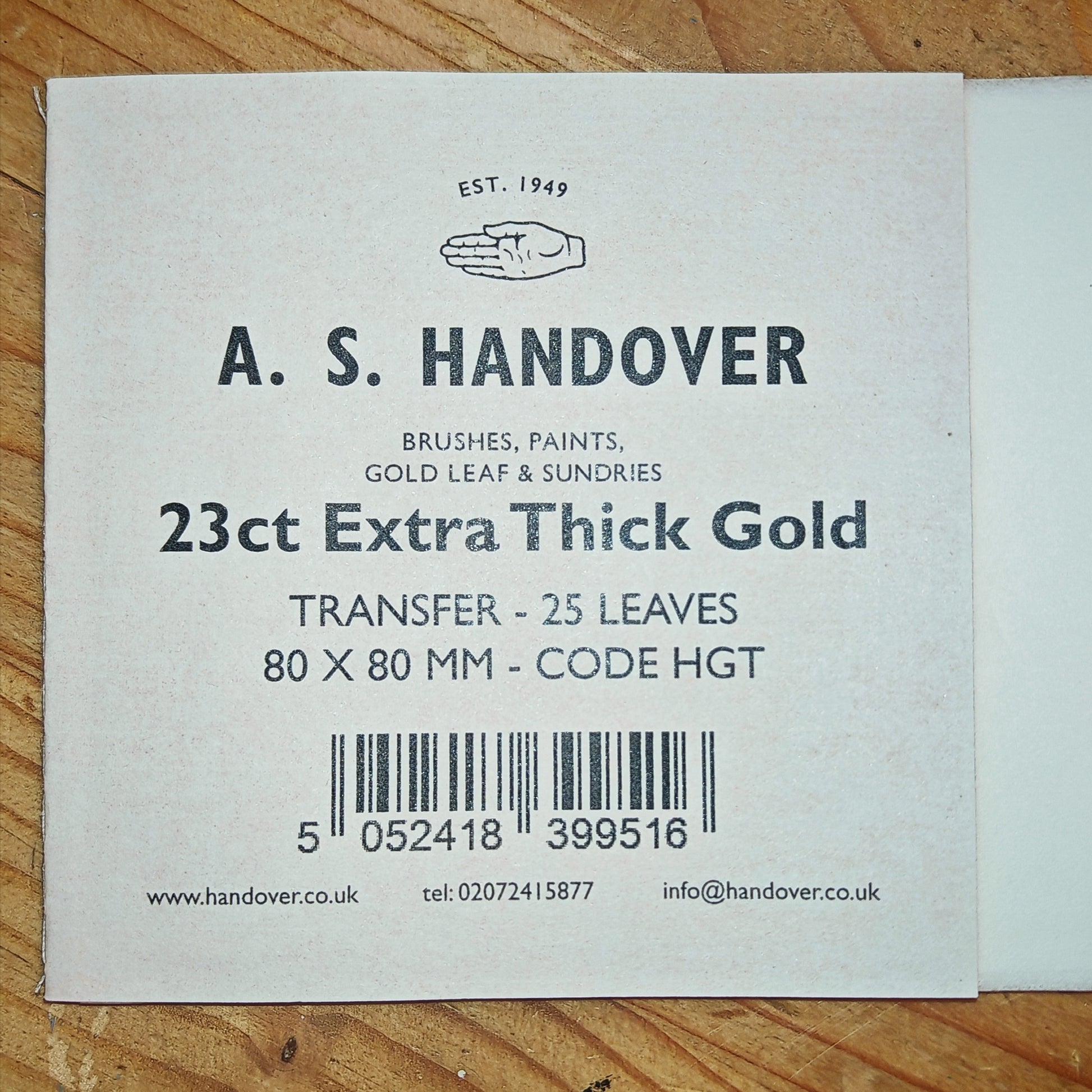 A.S. Handover product label for 23ct Extra Thick Gold on a wooden surface